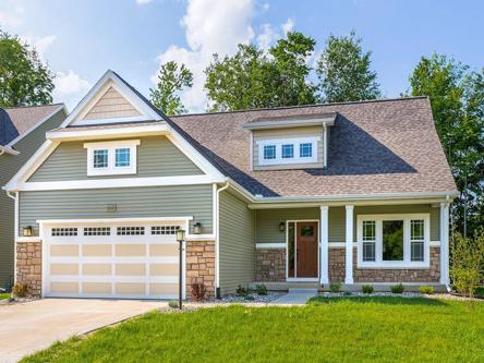 Residential brick, siding, and shingles home, that has two tone paint colors with a fresh coat of green gray color paint on the siding, a creamy beige color paint on the shakes near the roof pitch, and the trim painted bright white.