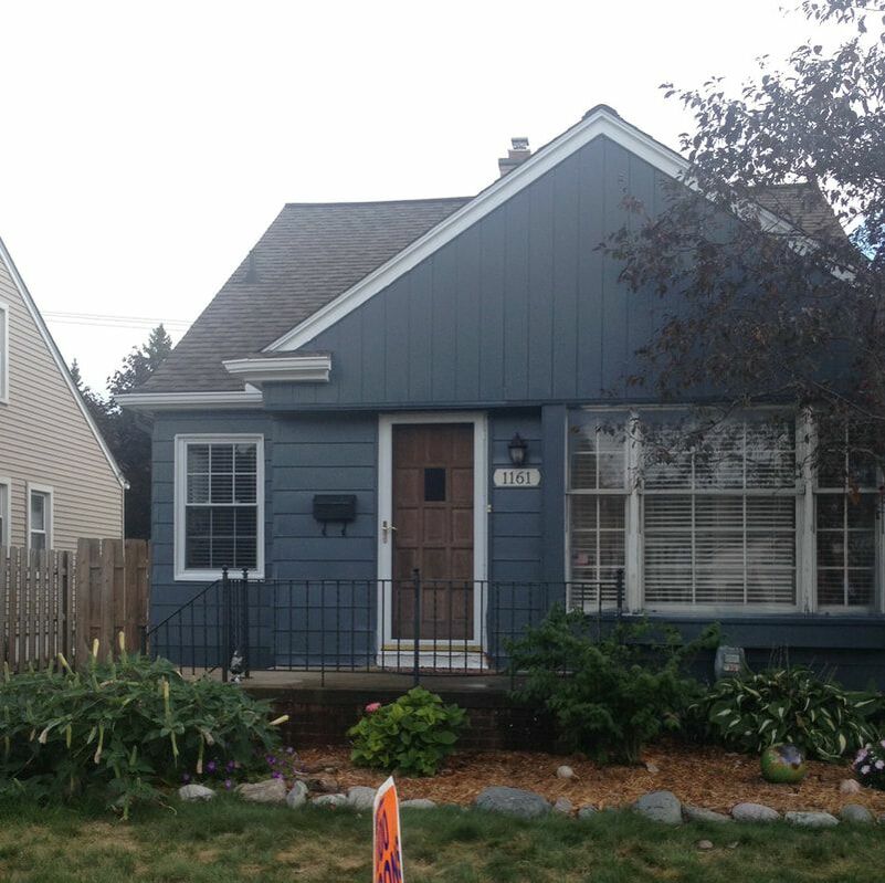 Residential home picture after getting a fresh coat of paint on aluminum siding. The siding was painted a dark blue gray with white trim. Absolutely transformed and brought character back to this charming bungalow style home. 